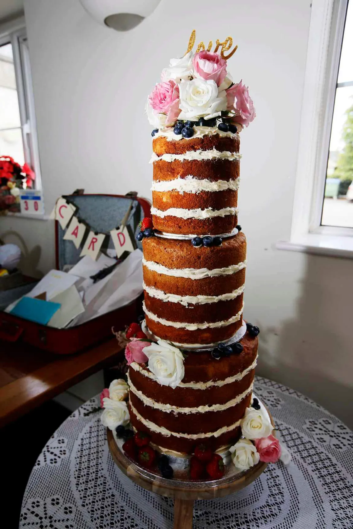 A tall naked wedding cake decorated with flowers