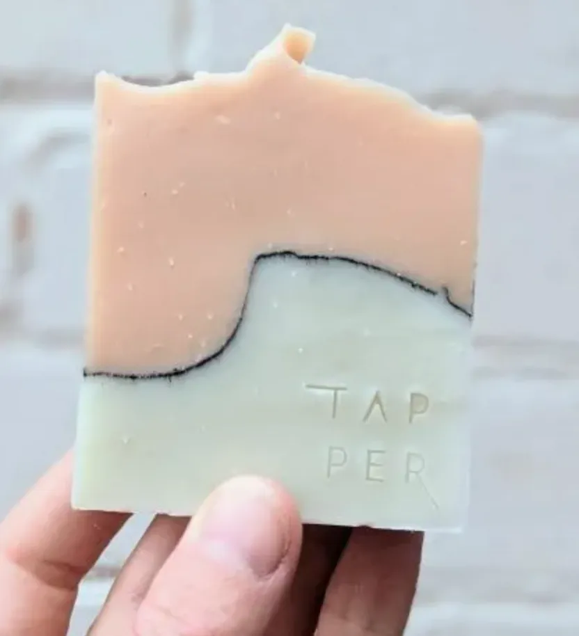A hand holding a bar of handmade Tapper soap