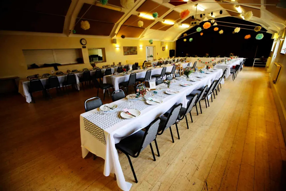Long tables laid for a wedding meal in a village hall