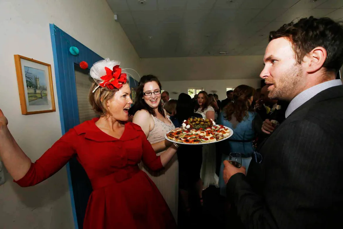 Wedding guests chatting, one carrying a tray of food