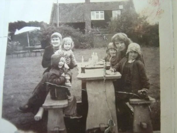 Old black and white photo of a family sitting round a garden table