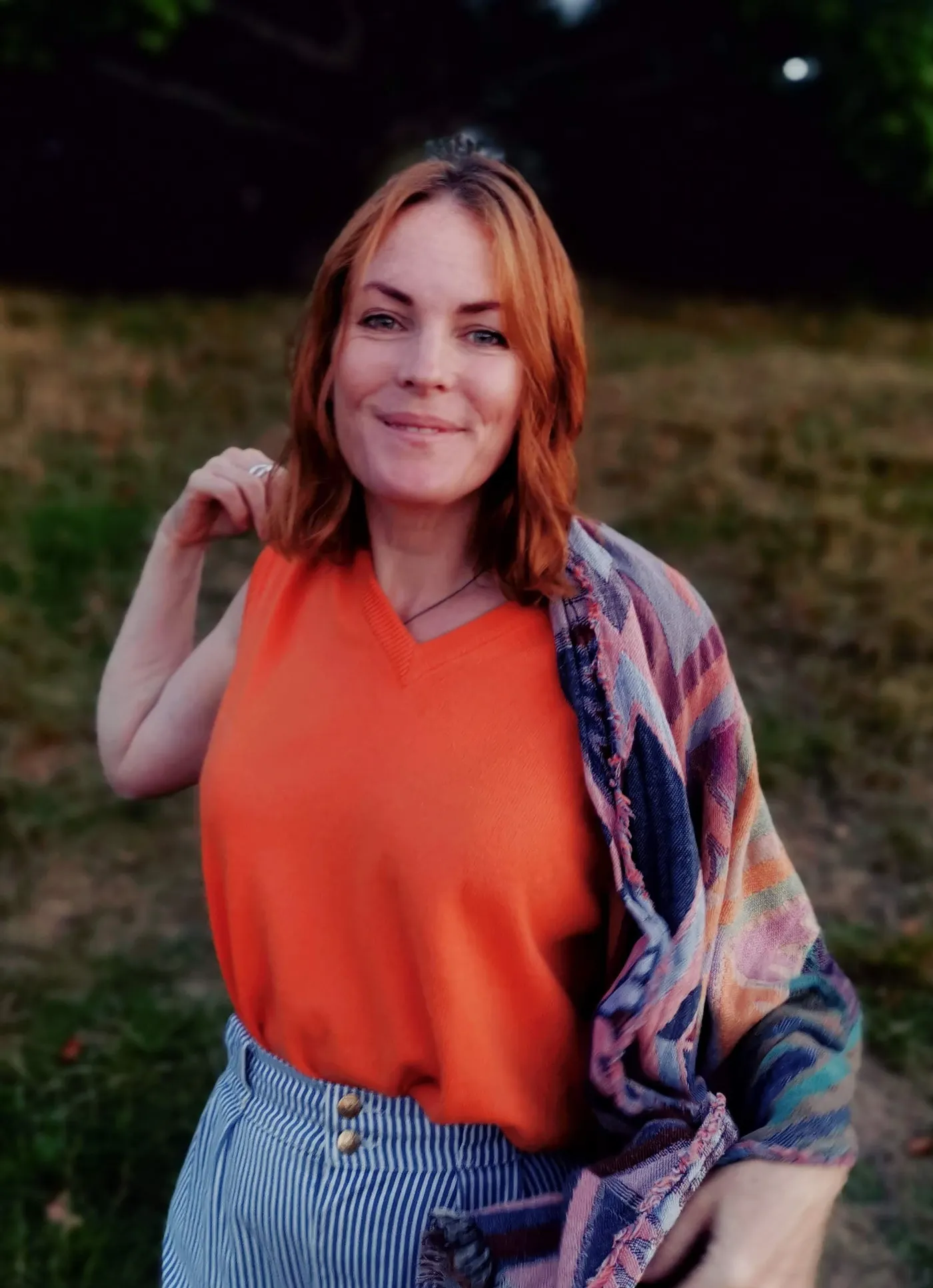 A woman in an orange top and a patterned scarf