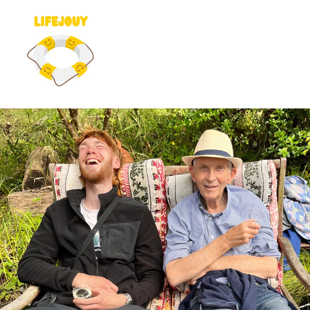 Two men laughing in deckchairs in a garden