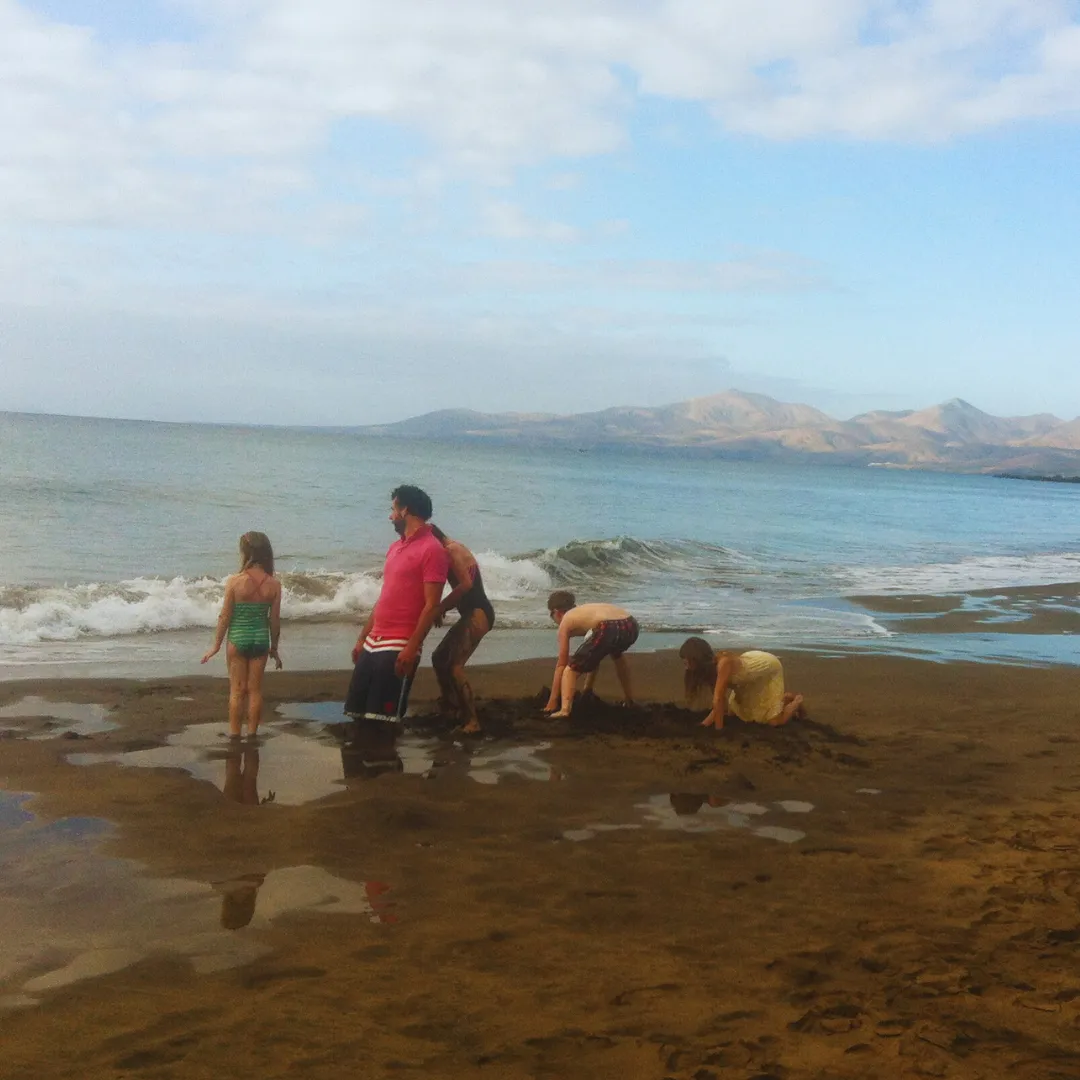 Children playing in the sea on a sandy beach with hills behind
