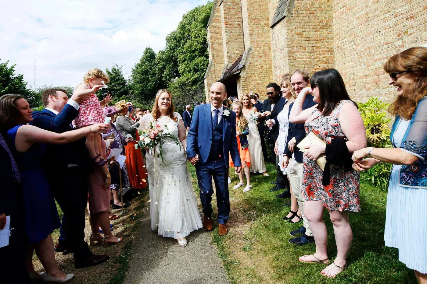 A bride and groom walking out of the church between cheering guests